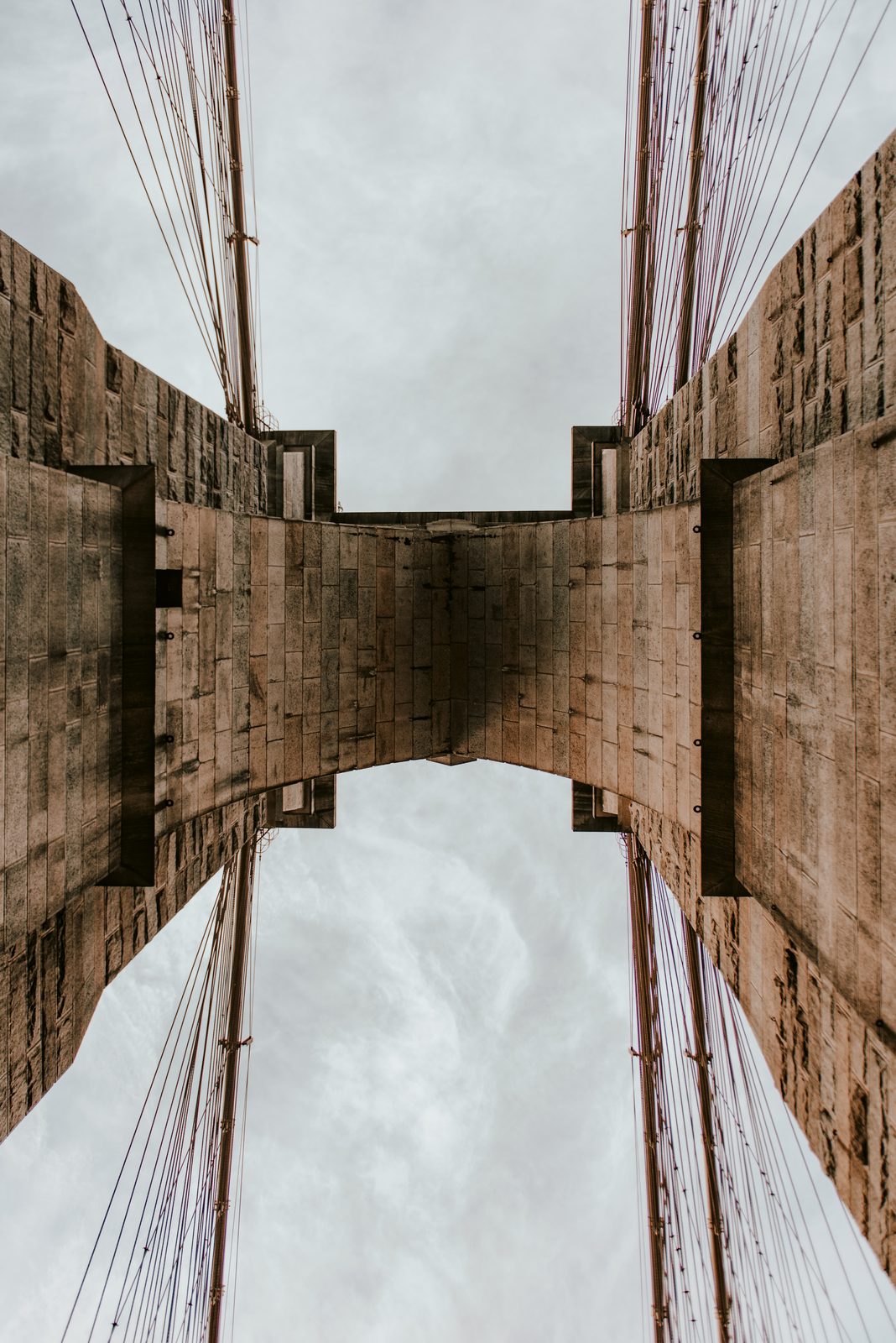 Looking straight up at a stone tower of the Brooklyn Bridge